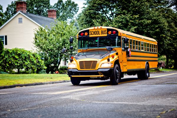 اتوبوس زرد مدرسه در حال رانندگی در امتداد خیابان