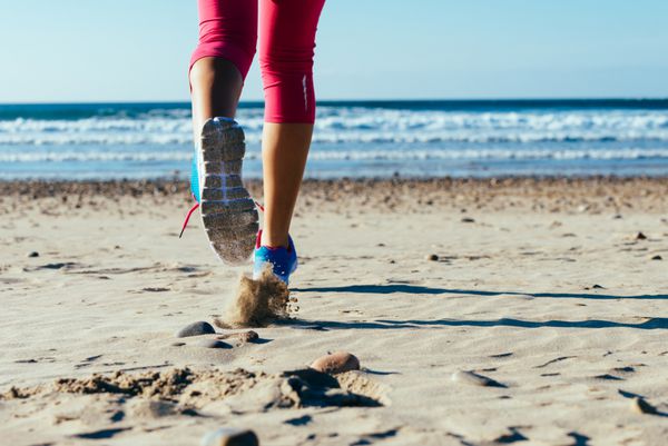 زن در حال دویدن سریع در ساحل پاهای دونده زن و جزئیات کفش ورزشی