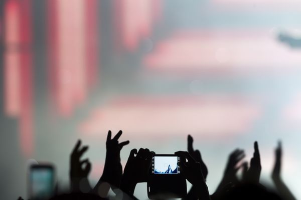 افرادی که در طول یک کنسرت عمومی سرگرمی موسیقی با تلفن هوشمند لمسی عکس می گیرند