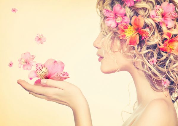دختر زیبایی گل های زیبا را در دستانش می گیرد دمیدن گل مدل مو با گل پرتره دختر فانتزی در رنگ های پاستلی پرتره تابستانی پری موهای بلند