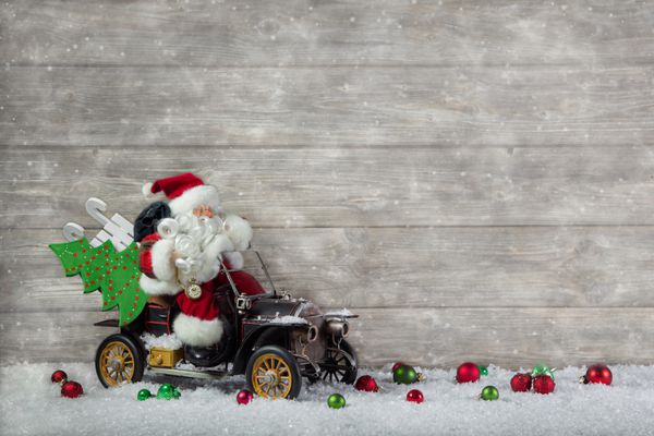 بابا نوئل در عجله با ماشینش استرس خرید کریسمس دکوراسیون با اسباب‌بازی‌های قدیمی قدیمی در پس‌زمینه چوبی