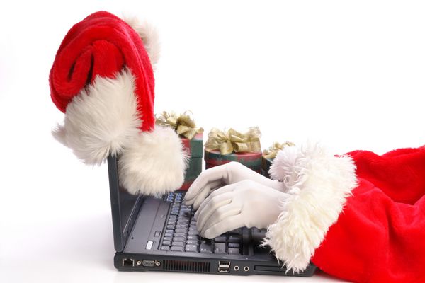 تایپ بابا نوئل با استفاده از لپ تاپ با کلاه بابا نوئل در گوشه ال سی دی لپ تاپ و ارائه در پس زمینه - جدا شده روی سفید