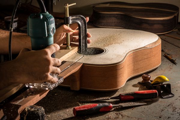 luthier کانالی را برای قرار دادن میله خرپایی در گردن گیتار برش می دهد