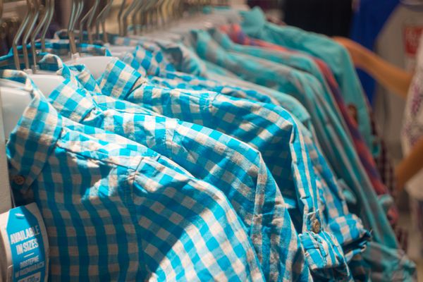 انواع پیراهن های هیپستر روی چوب لباسی در فروشگاه لباس های مد روز