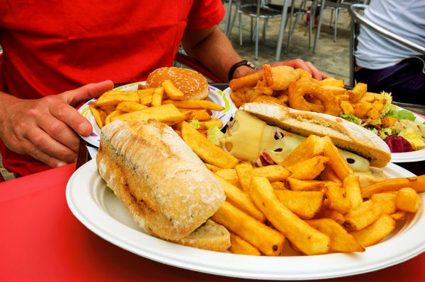 ناهار غذای ناسالم تعطیلات ماهی و چیپس در نان سیاباتا با پنیر آب شده همبرگر و میگوی سرخ شده مخلوط کالاماریس در رستوران کنار دریا در روز آفتابی برتن فرانسه
