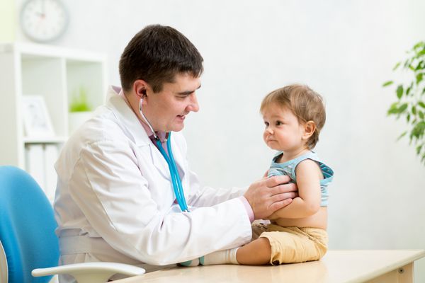 مرد متخصص اطفال در حال بررسی ضربان قلب پسر بچه با گوشی پزشکی