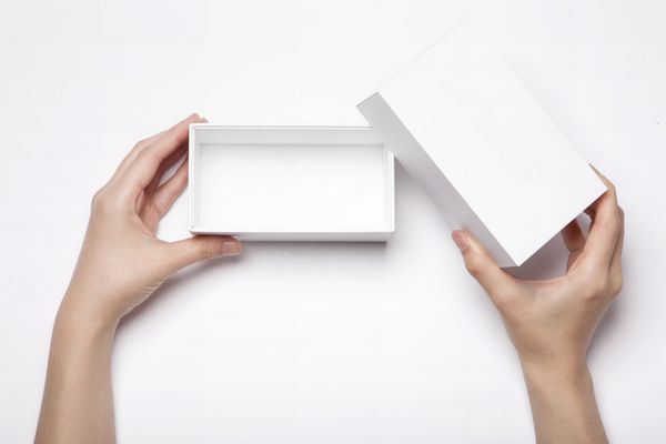 یک زن زن دختر با دو دست جعبه سفید خالی خالی را با نمای بالای استودیو جدا شده سفید جدا کرده و باز کنید