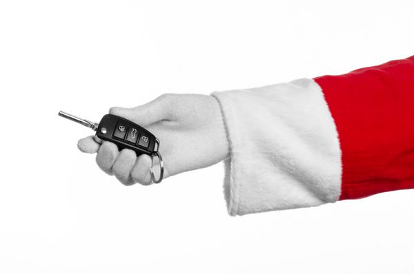 تم بابا نوئل دست بابا نوئل که کلید ماشین جدید را در پس زمینه سفید نگه می دارد