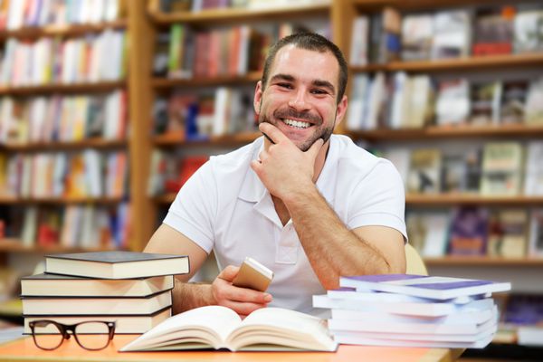 پرتره مردی شاد با پیراهن چوگان در یک کتابفروشی