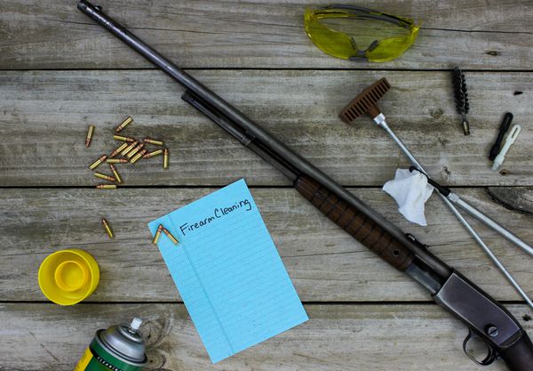 تفنگ با لوازم تمیز کردن و چک لیست تمیز کردن اسلحه گرم در زمینه چوبی روستایی