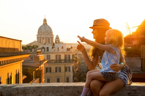 مادر و دختر بچه در خیابانی مشرف به پشت بام رم در غروب آفتاب نشسته اند و با انگشت اشاره می کنند