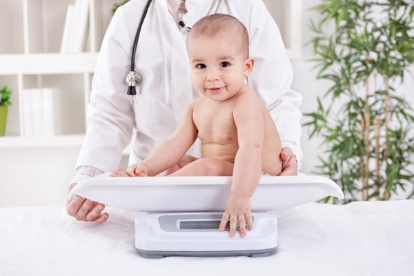 کودک کوچولوی شایان ستایش با پزشک اطفال زن اندازه گیری وزن
