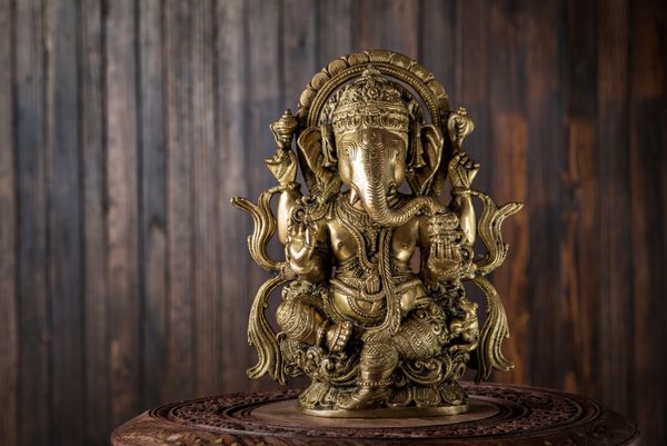 مجسمه زیبای هندو خدای خرد دانش و آغازهای جدید گانشا در مقابل پس زمینه چوبی