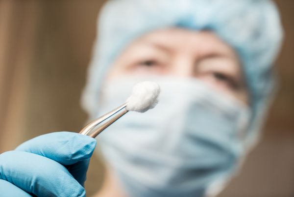 دندانپزشک زن با ابزاری که به بیمار خیره شده است