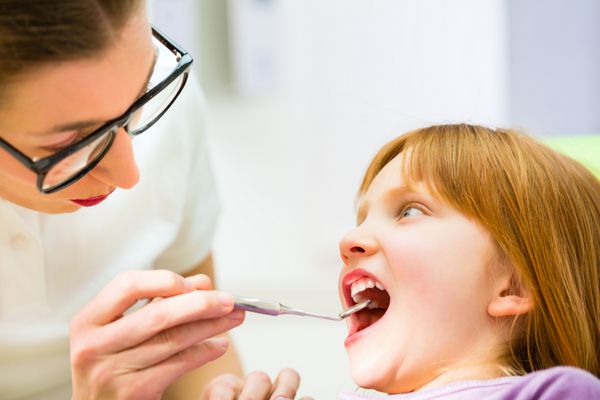 دندانپزشک در حال تمرین با کودک در جراحی دندان