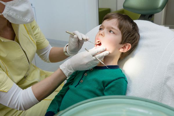 پسر بچه ای که دندان هایش را توسط دندانپزشک چک می کند