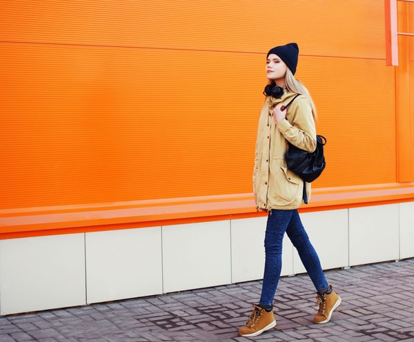 مد در فضای باز دختر جذاب هیپستر شیک در حال قدم زدن در شهر مقابل دیوار رنگارنگ شهری