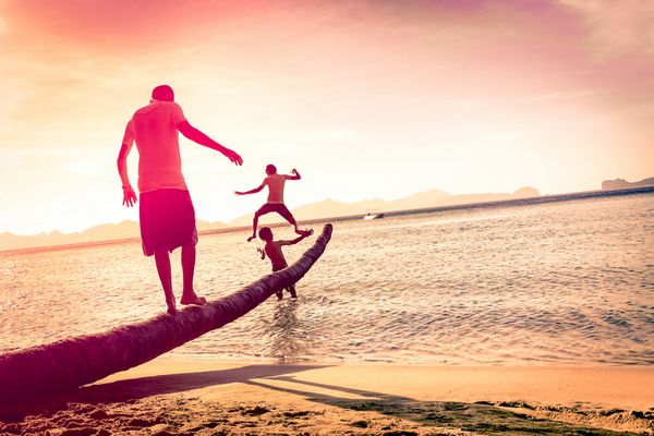 پدر با پسران در ساحل استوایی با افق کج - مفهوم اتحاد خانواده با مرد و فرزندان در حال تفریح با هم - سایه‌های غیرقابل تشخیص اصلاح شده - رنگ‌های فیلتر شده مارسالا
