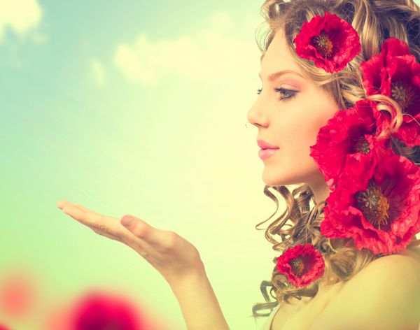 دختر زیبایی با مدل موی گل خشخاش قرمز و دستان باز دمیدن گل مدل مو با گل پرتره دختر فانتزی بر فراز آسمان آبی در فضای باز پرتره تابستانی پری موهای بلند