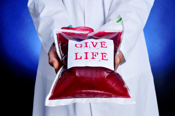 نمای نزدیک از یک پزشک که کیسه خون را با برچسبی با متن زندگی نشان می دهد