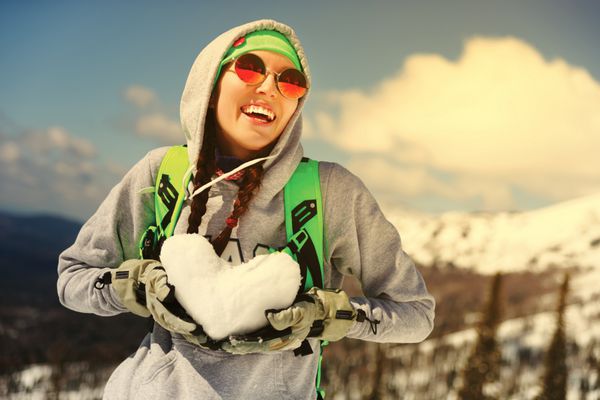 ورزش زمستانی اسنوبورد - پرتره دختر جوان اسنوبورد با قلب برفی در دست