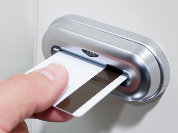 دست شخصی که یک کارت کلید نوار مغناطیسی را در قفل درب کلید کارت الکترونیکی وارد می کند