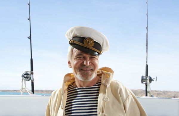 کاپیتان مرد ملوان خوشحال در پس زمینه قایق ماهیگیری
