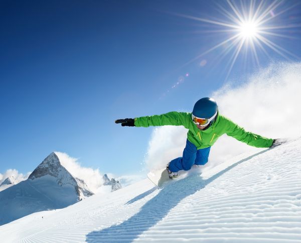 اسنوبورد در حال اسکی در کوه های بلند در یک روز آفتابی زیبا هوا و آسمان صاف پیست برفی آماده شده