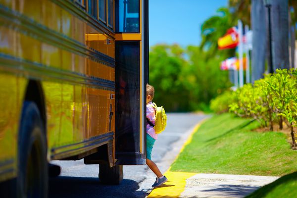 پسر جوان بچه سوار اتوبوس مدرسه آماده رفتن به مدرسه