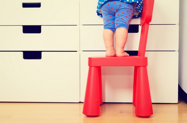 مفهوم ایمنی کودکان - دختر کوچک در حال بالا رفتن از صندلی کودک