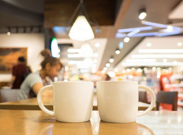 فنجان قهوه روی میز چوبی در کافه با پس زمینه تار مفهوم سبک زندگی اوقات فراغت