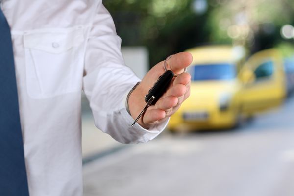 تاجر جوان موفق در حال ارائه کلید ماشین نمای نزدیک از دست راننده که کلید را نشان می دهد