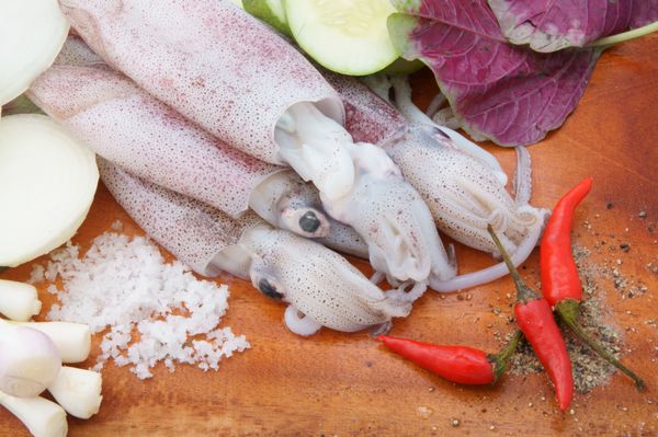 ماهی مرکب با سبزیجات روی تخته برش