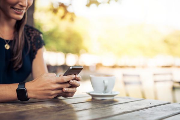 زن با استفاده از تلفن همراه در کافه ساعت هوشمند پوشیده است دست زن با گوشی هوشمند و قهوه