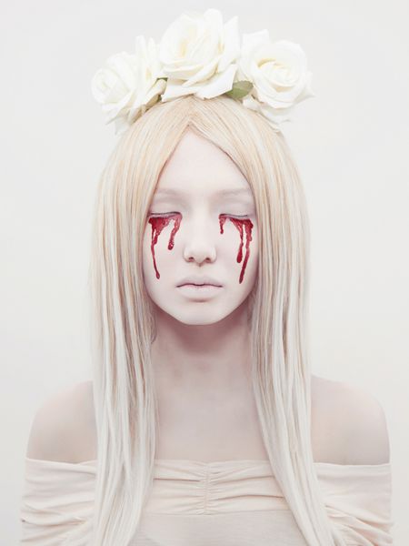 زن جوان زیبا با خون از چشمانش دختر هالووین ترسناک با گل