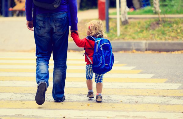 پدر در حال پیاده روی دختر کوچک با کوله پشتی به مدرسه یا مهد کودک