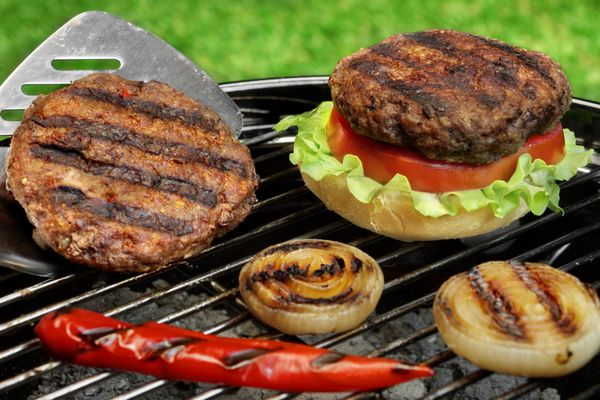 کفگیر و بیکیو همبرگر روی کباب پز زغالی مفهوم آشپزی میان وعده خوب برای مهمانی تابستانی در فضای باز یا پیک نیک چمن حیاط خلوت در پس زمینه