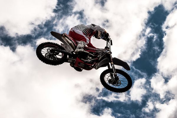 یک سوارکار حرفه ای در مسابقات fmx موتوکراس آزاد خلبان موتور کراس در یک پیچ در هنگام غروب آفتاب پرش موتور کراس سوار در آسمان آبی با ابرها موتور کراس سوار زباله های موتورکراس r