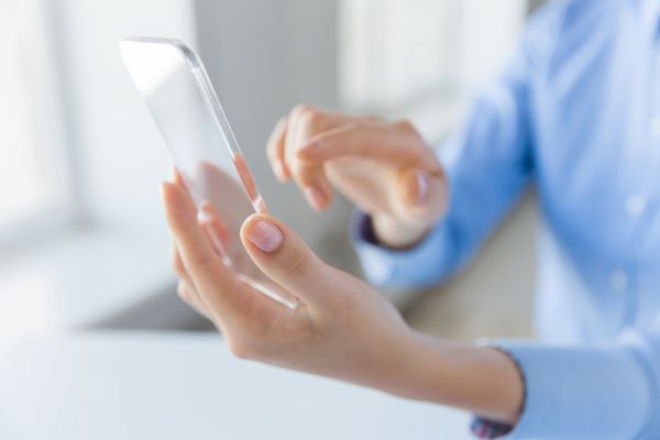 مفهوم کسب و کار فناوری و مردم - نمای نزدیک از دست زنی که گوشی هوشمند شفاف را در دفتر گرفته و نشان می دهد