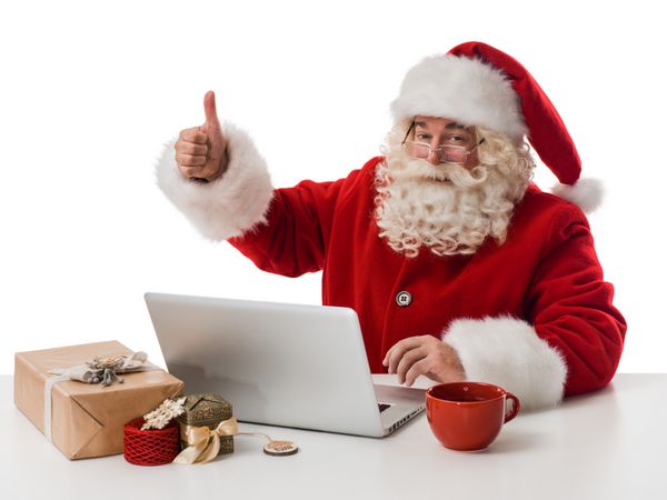 بابا نوئل در حال کار با لپ تاپ روی میز پرتره نزدیک جدا شده در زمینه سفید