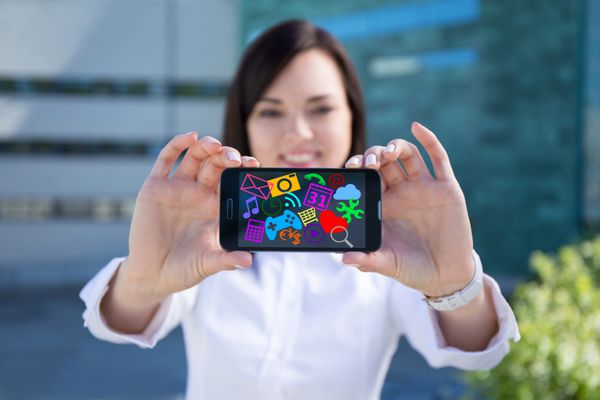 زن زیبای تجاری جوان در حال نمایش تلفن هوشمند مدرن با نمادها و برنامه های رسانه ای رنگارنگ