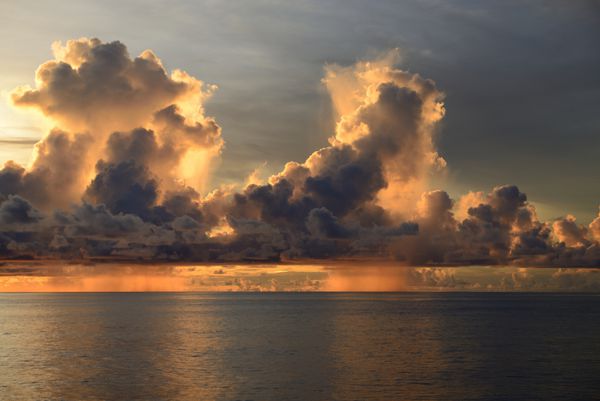 یک آسمان شگفت‌انگیز عصر با یک آسمان قرمز تیره بارانی و ابری روشن شده است این تصویر در اقیانوس آرام نزدیک گوام گرفته شده است