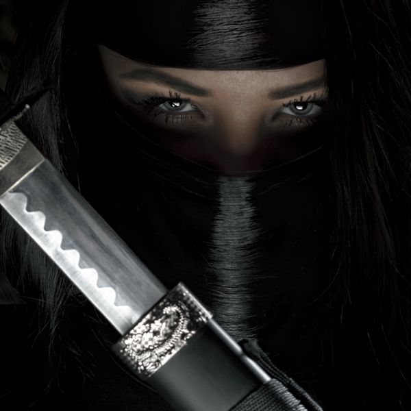 دختر یا زن با لباس جنگجوی نینجا سیاه شمشیر کاتانا را در دست دارد