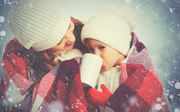 مادر و فرزند دختر خانواده شاد در حال نوشیدن چای در یک پیاده روی زمستانی در خارج از منزل