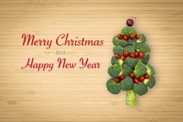 ایده مفهومی جشن تزیین سبزیجات به شکل درخت کریسمس طرح نمادین تزئینی سبزیجات کریسمس مبارک و کریسمس مبارک با غذای قرمز و سبز روی پس زمینه تخته برش چوب