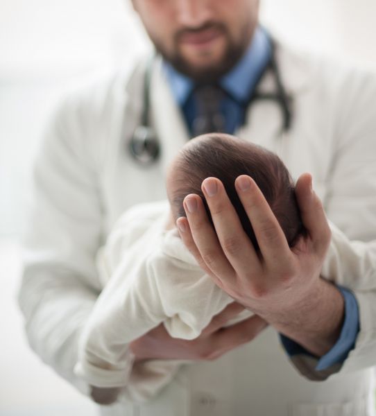 پزشک اطفال که یک نوزاد پسر زیبا را در آغوش گرفته است