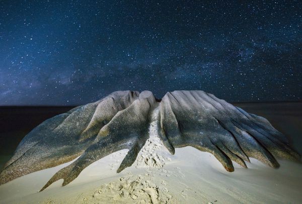تخته سنگ گرانیتی با شکل زیبا توسط دریا در ساحل آنس سورس دارجنت جزیره لا دیگ سیشل شسته می شود شب با ستاره ها
