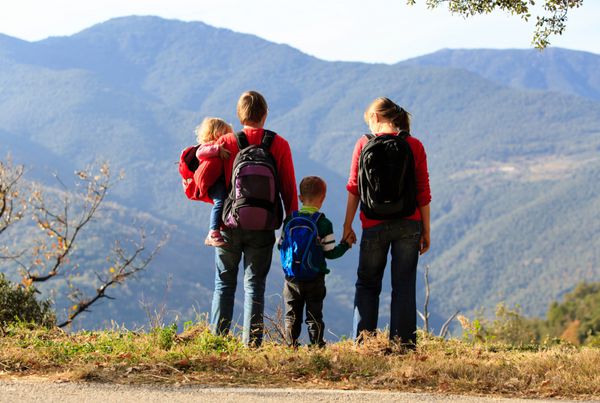 خانواده با دو بچه که در کوهستان پیاده روی می کنند