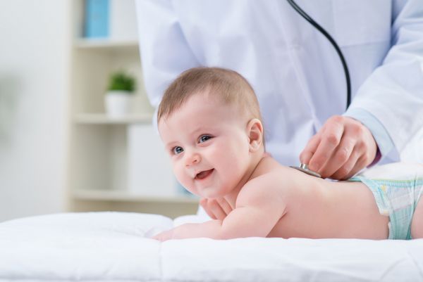متخصص اطفال در حال معاینه نوزاد