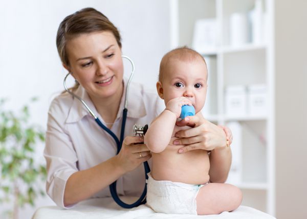 دکتر با گوشی پزشکی به صدای قلب کودک گوش می دهد